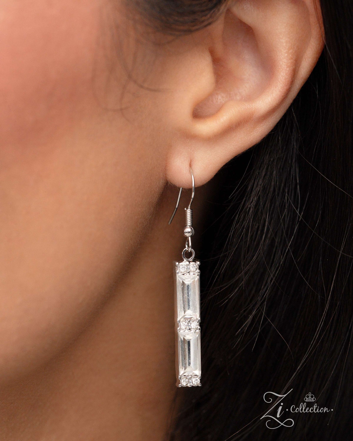 The Leslie White Rhinestone 2024 Zi Necklace - Paparazzi Accessories Item #Z2402 Shimmery bars, made up of stacks of emerald-cut white gems, slide along two skinny snake chains, with sleek metallic beads separating each one. Duos of dainty white rhinestones are stamped across the surface of each layer, emitting a timeless twinkle, resulting in a collision of light-reflecting texture and sheen. Features an adjustable clasp closure. Sold as one individual necklace. Includes one pair of matching earrings.