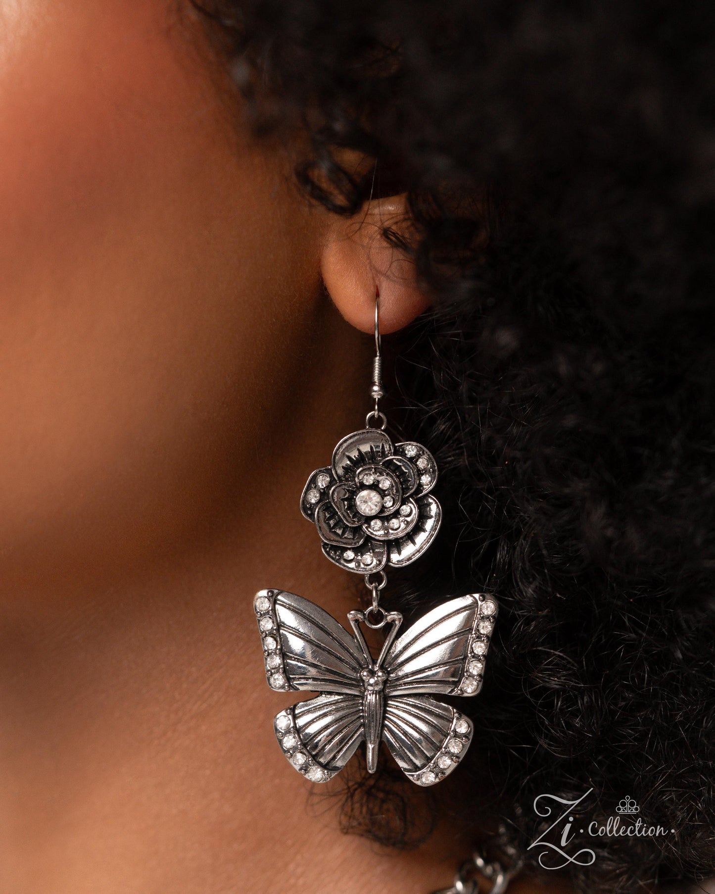 The McKayla Silver Butterfly 2024 Zi Necklace - Paparazzi Accessories Item #Z2407 A whimsical collection of shimmery luminescent and intricately detailed silver charms — including rhinestone-embellished flowers and airy butterflies — dance from a chunky silver chain that adorns the collar in two layers, creating a boisterous, blissful fringe. Features an adjustable clasp closure. Sold as one individual necklace. Includes one pair of matching earrings. Named after the 2024 Seize the Spotlight winner, Mc