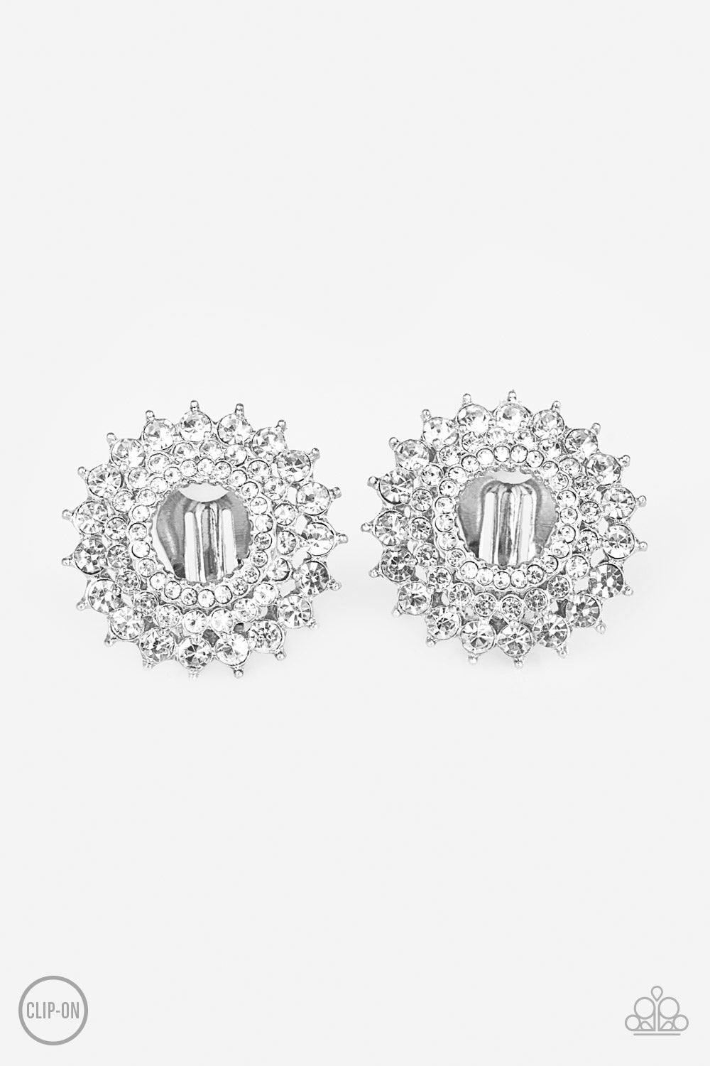 Buckingham Beauty White Clip-On Earring - Paparazzi Accessories Gradually increasing in size, glassy white rhinestones are encrusted along three stacking silver frames for a regal look. Earring attaches to a standard clip-on fitting. All Paparazzi Accessories are lead free and nickel free! Sold as one pair of clip-on earrings.