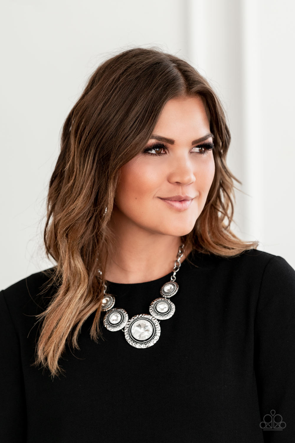 Global Glamour White Necklace - Paparazzi Accessories. Gradually increasing in size, dramatically oversized white gems are pressed into the centers of hammered and silver studded frames. The blinding frames link below the collar for a glamorous, statement-making finish. Features an adjustable clasp closure. All Paparazzi Accessories are lead free and nickel free! Sold as one individual necklace. Includes one pair of matching earrings.