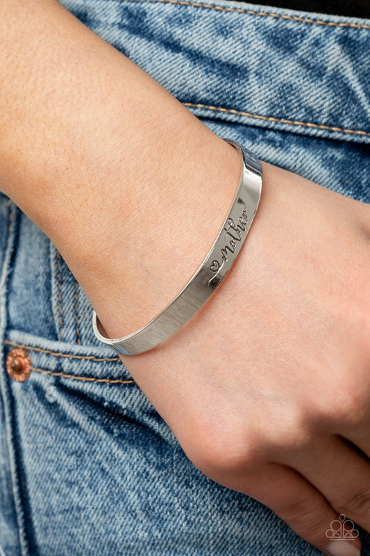Sweetly Named Silver Cuff Bracelet - Paparazzi Accessories  A dainty silver cuff is stamped in a heart and the word, "Mother," creating a sentimental centerpiece around the wrist.  Sold as one individual bracelet.