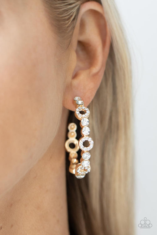 Swoon-Worthy Sparkle Gold Hoop Earring - Paparazzi Accessories  Dainty round gold frames encrusted with sparkling white rhinestones act as show-stopping accents around a gold hoop of white rhinestones culminating in a swoon-worthy finish. Earring attaches to a standard post fitting. Hoop measures approximately 1 1/2" in diameter.  Sold as one pair of hoop earrings.