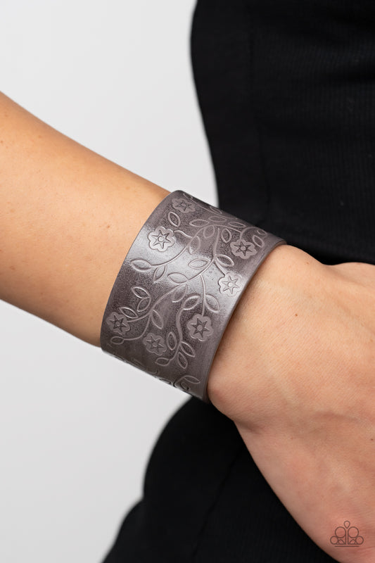 Rosy Wrap Up Silver Wrap Bracelet - Paparazzi Accessories  A flowery and leafy motif blooms across the front of a distressed gray leather band, resulting in a rustic floral centerpiece around the wrist. Features an adjustable snap closure.  Sold as one individual bracelet.