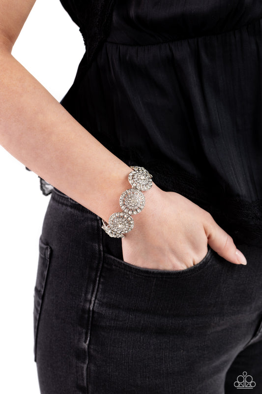 Executive Elegance White Stretch Bracelet - Paparazzi Accessories  Featuring a wheel motif, concaved silver discs embossed in an explosion of white rhinestones slide along a stretchy band around the wrist for a hint of dazzling refinement.  Sold as one individual bracelet.  P9RE-WTXX-576XX