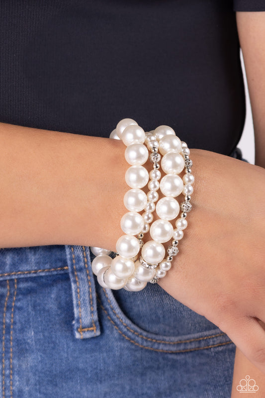 Vastly Vintage White Pearl Bracelet - Paparazzi Accessories  Infused with white rhinestone-encrusted silver beads, white rhinestone-encrusted discs, and textured silver beads, a bubbly collection of mismatched white pearls are threaded along stretchy bands around the wrist for a vintage-inspired layered look.  Sold as one set of four bracelets.  P9RE-WTXX-565XX