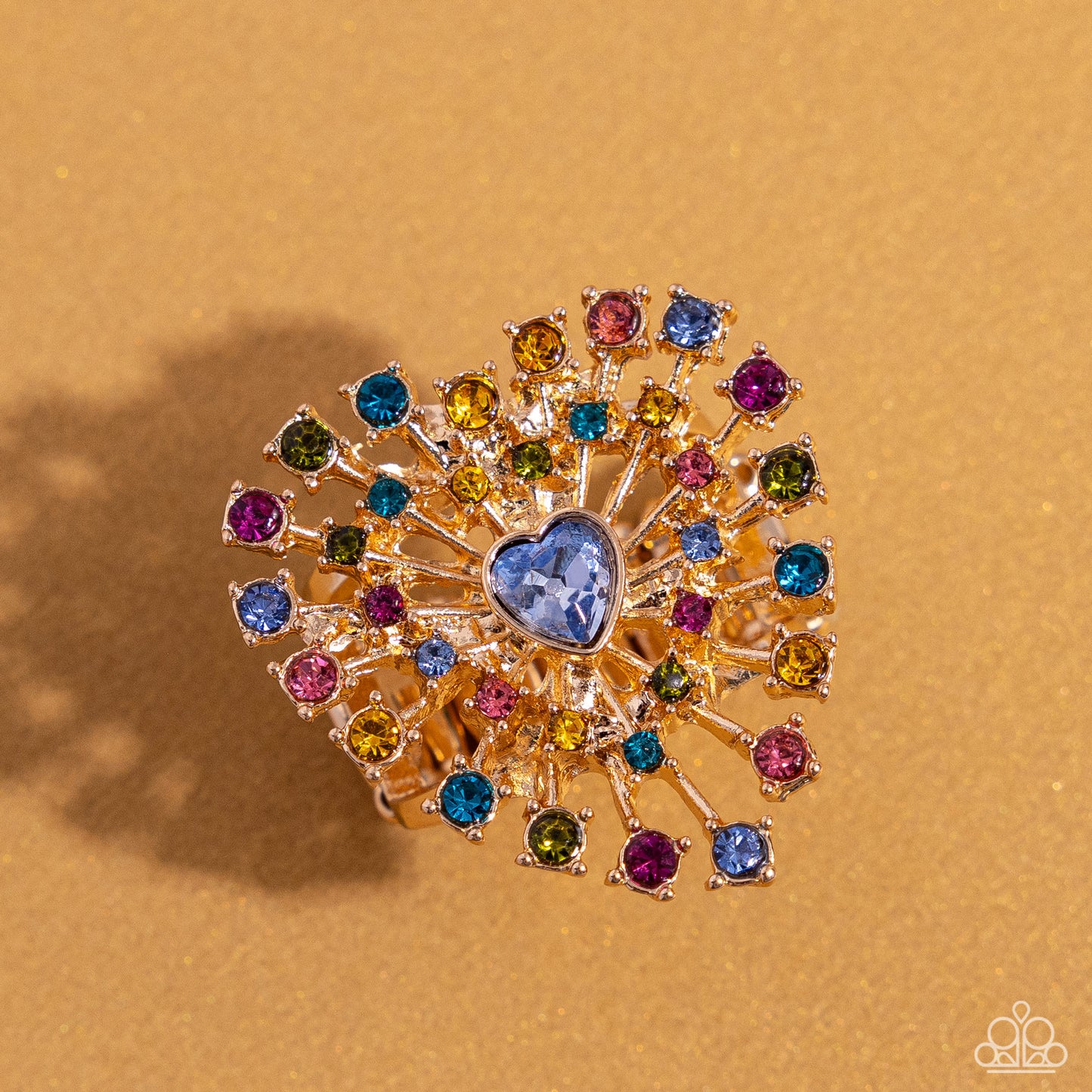 Bewitching Beau Multi Heart Ring - Paparazzi Accessories Set in pronged gold square fittings, multicolored round rhinestones circle a light sapphire heart gem in a sunburst pattern for a bewitching display. Features a stretchy band for a flexible fit. Sold as one individual ring. SKU: P4ST-MTXX-028XX *LOP January 2024