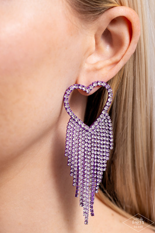 Sumptuous Sweethearts Purple Heart Post Earring - Paparazzi Accessories Glassy white rhinestones, encrusted along the front of a purple heart frame, create a flirty centerpiece. Staggered rows of white rhinestones pressed in delicate purple square fittings cascade from the sparkly centerpiece, adding glitzy movement to the romantic piece. Earring attaches to a standard post fitting. Sold as one pair of post earrings. SKU: P5PO-PRXX-021XX