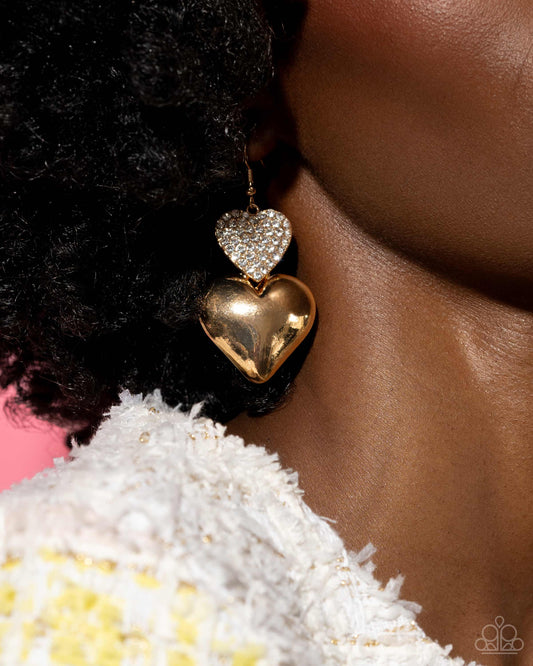 Charming Connection Gold Heart Earring - Paparazzi Accessories  Delicately dusted in white rhinestones, a blinding gold heart frame delicately links with a larger sleek gold heart for a flirtatiously layered look. Earring attaches to a standard fishhook earring.  Sold as one pair of earrings.  P5RE-GDXX-262XX