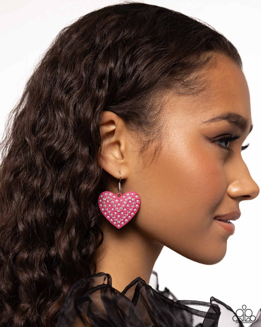 Romantic Reunion Pink Heart Earring - Paparazzi Accessories  A Pink Peacock painted heart is covered in rows of tiny white rhinestones and pink pearls, emitting radiant shimmer as it swings from the ear. Earring attaches to a standard fishhook fitting.  Sold as one pair of earrings.  SKU: P5RE-PKXX-270XX