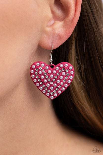 Romantic Reunion Pink Heart Earring - Paparazzi Accessories  A Pink Peacock painted heart is covered in rows of tiny white rhinestones and pink pearls, emitting radiant shimmer as it swings from the ear. Earring attaches to a standard fishhook fitting.  Sold as one pair of earrings.  SKU: P5RE-PKXX-270XX