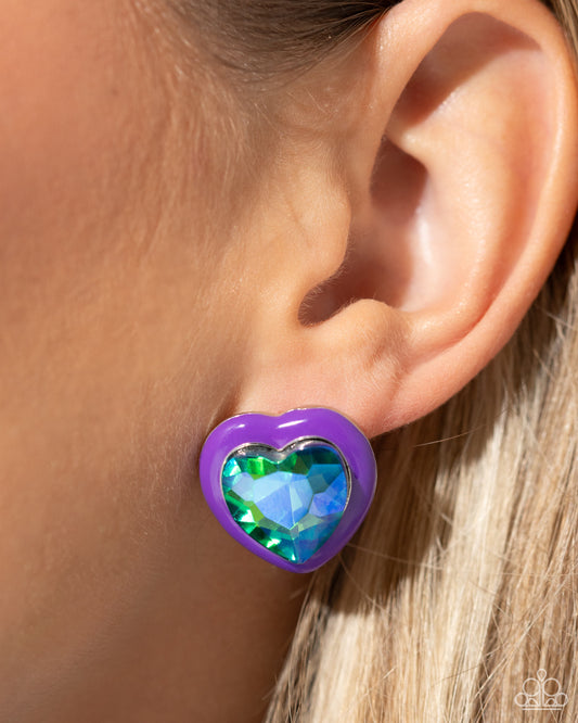 Heartfelt Haute Purple Post Earring - Paparazzi Accessories Pressed in a border of purple paint, an oversized UV shimmery heart gem glimmers from the ear, resulting in a romantic-inspired display. Earring attaches to a standard post fitting. Sold as one pair of post earrings. SKU: P5PO-PRXX-025UM Get The Complete Look! Necklace: "Heartfelt Hope - Purple" (Sold Separately)