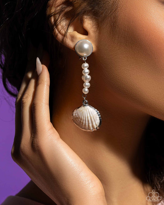 Oceanic Occasion White Seashell Clip-On Earring - Paparazzi Accessories  Pressed in a silver fitting, an oversized white pearl gives way to a lengthened strand of glossy classic and baroque white pearls. Bordered in a shimmery silver finish, a white seashell swings from the bottom of the pearly strand for a classy, coastal statement. Earring attaches to a standard clip-on fitting.  Sold as one pair of clip-on earrings.  SKU: P5CO-WTXX-144XX