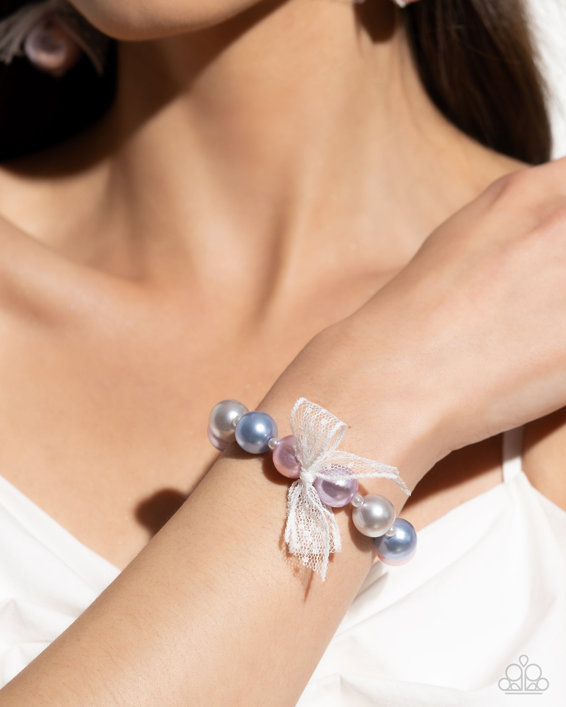 Girly Glam Multi Pearl Stretch Bracelet - Paparazzi Accessories Strung along an elastic stretchy band, a collection of glossy colorful pearls alternate with dainty white pearls along the wrist. An airy, chiffon white ribbon is tied in the center of the pearls for a refined finish. This bracelet would be the perfect accessory for a gender reveal or for a mom with boys and girls! Sold as one individual bracelet. SKU: P9RE-MTXX-162VV Get The Complete Look! Earring: "Elegance Ease - Multi" (Sold Separately)