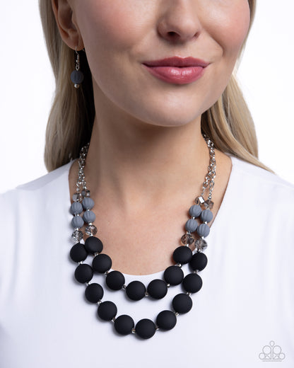Whimsically Wealthy Black Necklace - Paparazzi Accessories Smoky faceted beads, silver beads, Sharkskin beads, and black matte beads are infused along classic silver chains that layer below the neckline for a colorfully charismatic look. Features an adjustable clasp closure. Sold as one individual necklace. Includes one pair of matching earrings. SKU: P2WH-BKXX-325XX