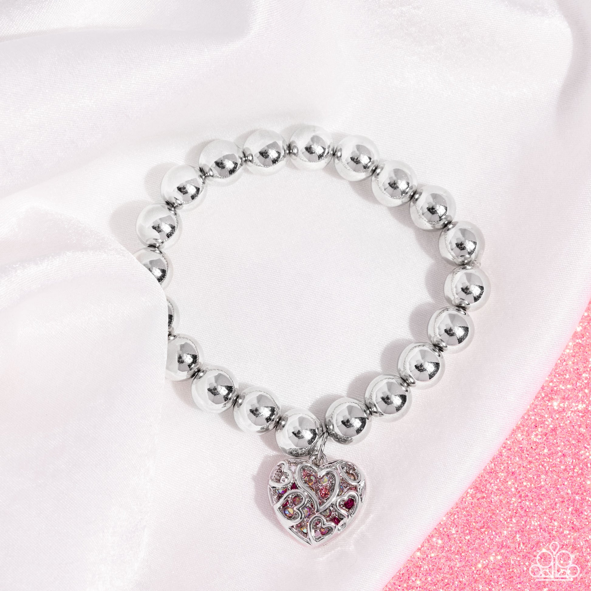 Fleeting Filigree Pink Stretch Bracelet - Paparazzi Accessories  Infused along an elastic stretchy band, a collection of bold silver beads glimmer from the wrist. Fuchsia, light rose, pink iridescent rhinestones, and dainty silver studs peek out from underneath a silver heart filigree cover for a whimsical, romantic finish. Due to its prismatic palette, color may vary.  Sold as one individual bracelet.  P9RE-PKXX-334XX