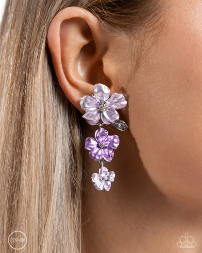 Balanced Bouquet Purple Flower Clip-On Earring - Paparazzi Accessories  Dotted with silver-studded centers, metallic light purple and lavender flowers bloom and alternate, gradually decreasing in size as they cascade below the ear. The largest flower blossoms across a textured collection of silver leaves, invoking a festive spirit. Earring attaches to a standard clip-on fitting.  Sold as one pair of clip-on earrings.  P5CO-PRXX-027ZR