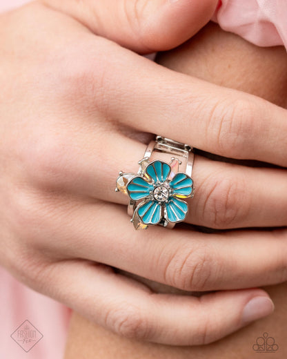 Hamptons Holiday - Blue Item #P4WH-BLXX-218AD   Featuring a white rhinestone center, a blue-painted silver flower radiates from an airy silver band. Opalescent topaz and pink gems in various cuts blossom outward from the blue flower in silver-pronged fittings for a dreamy, coastal-inspired centerpiece. Features a stretchy band for a flexible fit.  Sold as one individual ring.