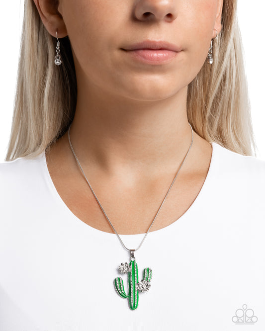 Carefree Cactus Green Necklace - Paparazzi Accessories  Featuring white rhinestone detailing, a green-painted cactus pendant, embellished with silver flowers glides along a dainty silver snake chain for a free-spirited fashionable display. Features an adjustable clasp closure.  Sold as one individual necklace. Includes one pair of matching earrings.  P2SE-GRXX-291XX