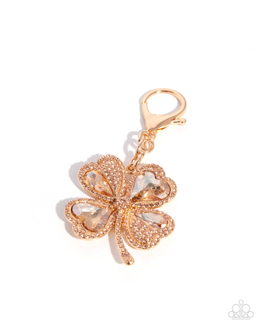 Rose gold four-leaf clover purse charm with clear gemstones on a white background