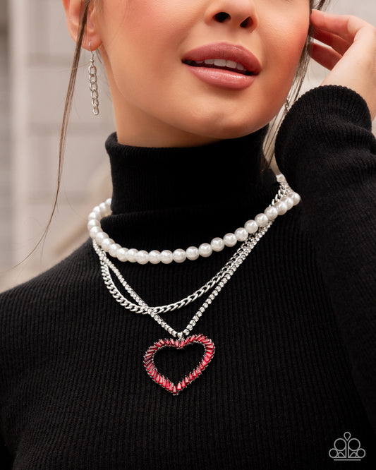 Y2K Year Red Heart Necklace - Paparazzi Accessories  Bold layers of a glistening silver curb chain, white rhinestones pressed in silver square fittings, and glossy white pearls, fall across the chest creating an edgy refined effect. Chiseled red gems in pronged silver fittings twist into an airy heart pendant that glides along the lowermost chain for a romantic finish. Features an adjustable clasp closure.  Sold as one individual necklace. Includes one pair of matching earrings.  P2ST-RDXX-142XX