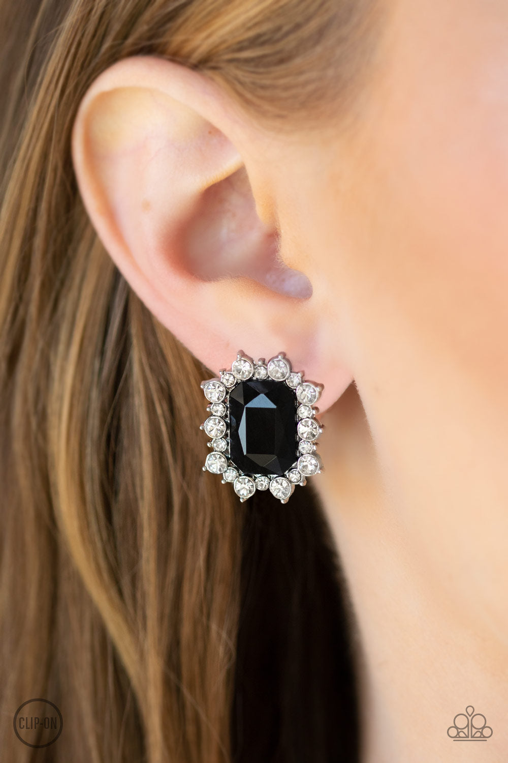 Prime Time Shimmer - Black Item #E381 A border of glassy white rhinestones spin around a regal emerald-cut black rhinestone center for a refined look. Earring attaches to a standard clip-on fitting. All Paparazzi Accessories are lead free and nickel free!  Sold as one pair of clip-on earrings.