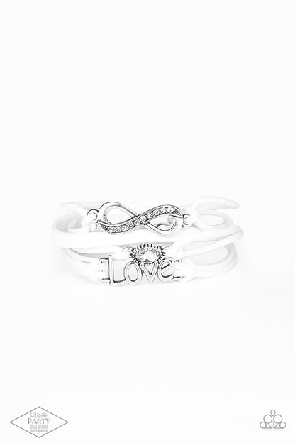 Infinitely Irresistible White Bracelet - Paparazzi Accessories  Strands of white suede knot around silver charms, including a glittery infinity charm, a solitaire rhinestone, and a charm whimsically spelling out “love” across the wrist. Features an adjustable clasp closure.  Sold as one individual bracelet. This Fan Favorite is back in the spotlight at the request of our 2021 Life of the Party member with Black Diamond Access, Miranda B.