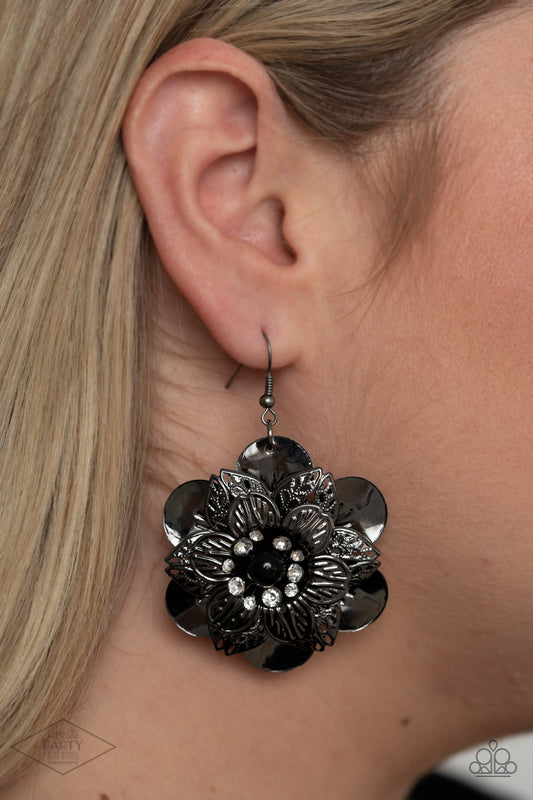 Midnight Garden Black Flower Earring - Paparazzi Accessories. Sleek gunmetal petals with a variety of textures are layered to create a dramatic flower. A single black bead bordered by a ring of rhinestones anchors the design while adding unmatched sparkle.  All Paparazzi Accessories are lead free and nickel free!  Sold as one pair of earrings. This Fan Favorite is back in the spotlight at the request of our 2020 Life of the Party member with Black Diamond Access, Monica C.