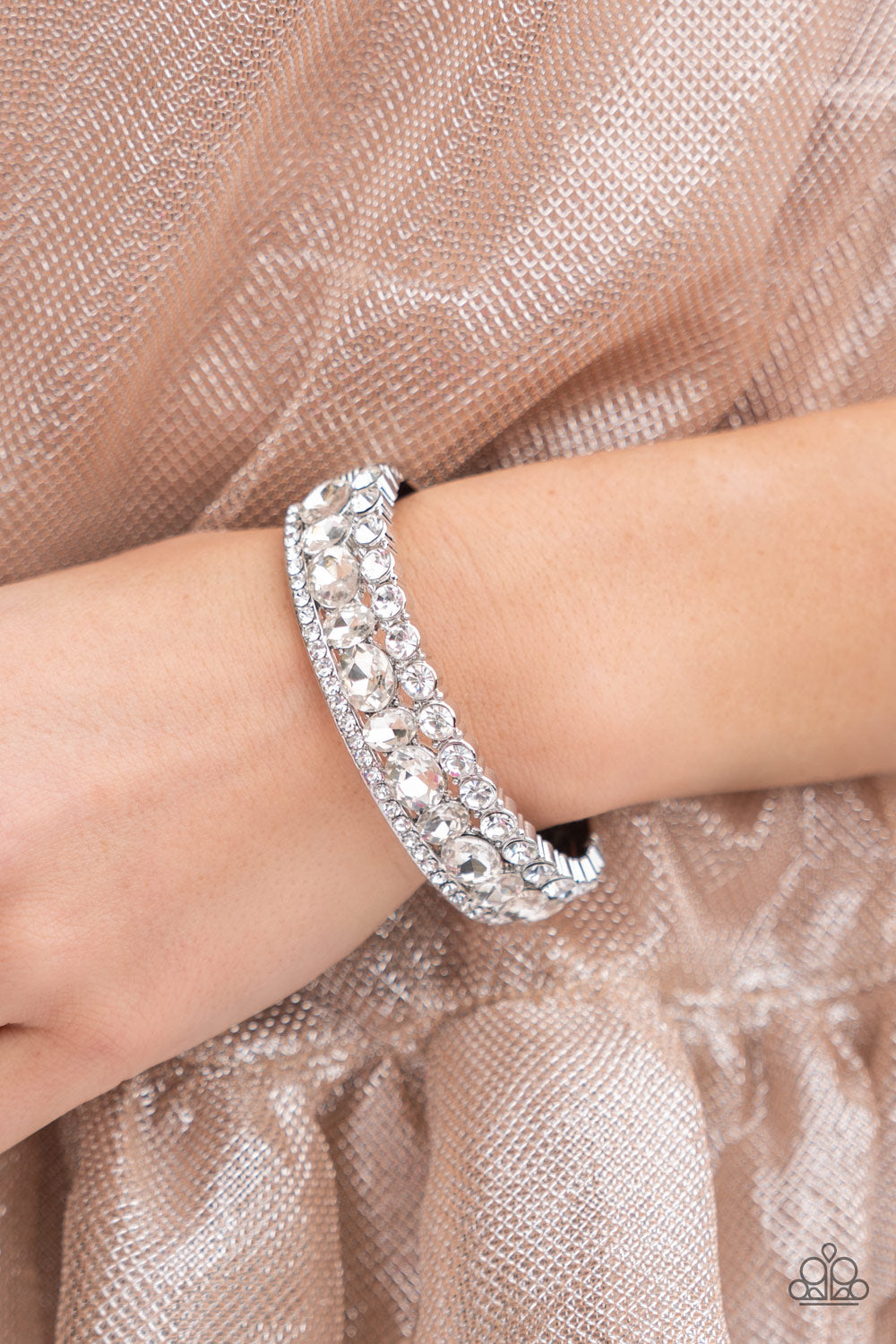 Mega Megawatt White Bracelet - Paparazzi Accessories  Three blinding rows of mismatched white rhinestones dramatically stack across the wrist, coalescing into a majestic bangle-like centerpiece. Features a hinged closure.  Sold as one individual bracelet.