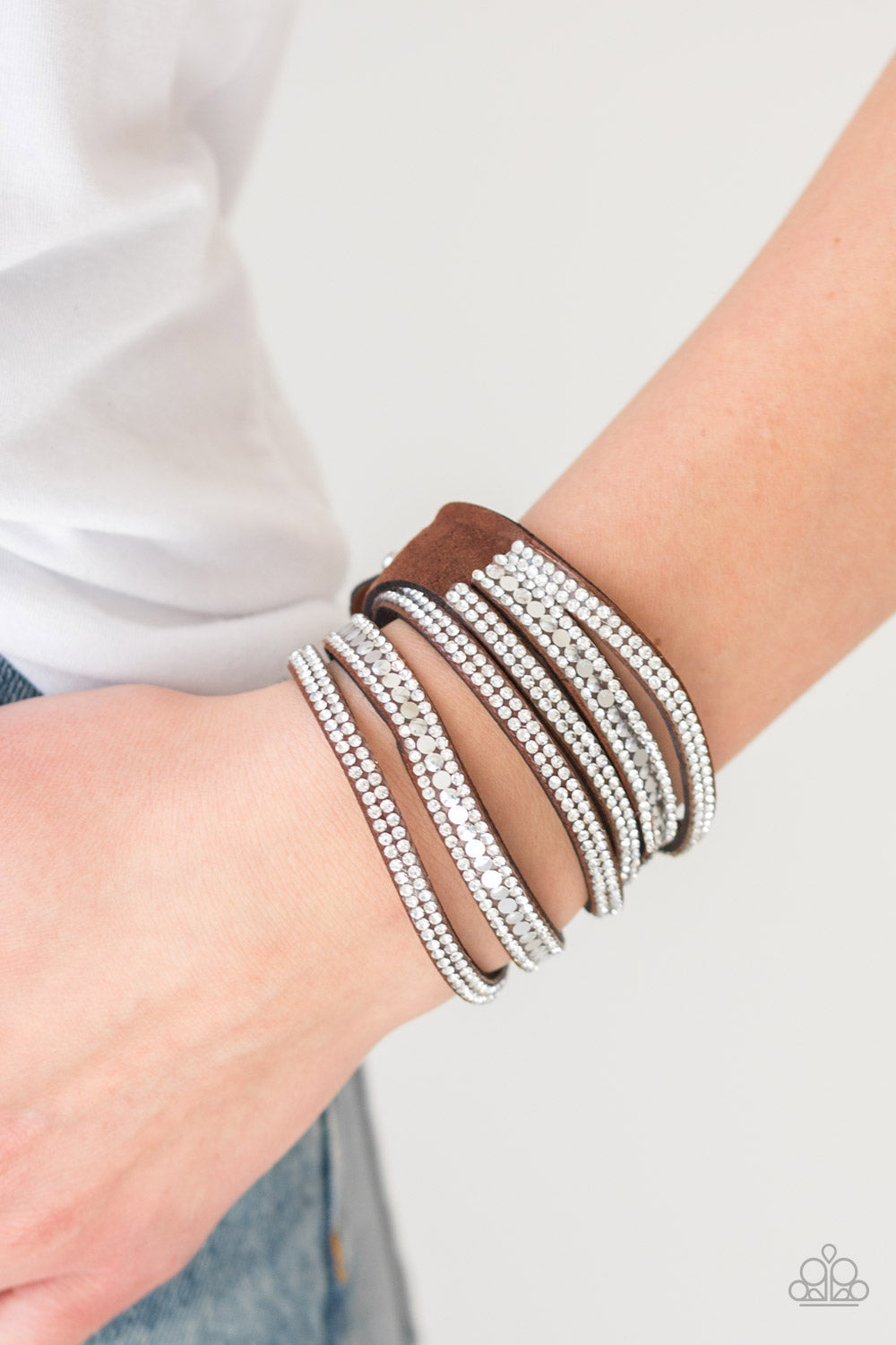 Rock Star Attitude Brown Wrap Bracelet - Paparazzi Accessories  Encrusted in rows of glassy white rhinestones and flat silver studs, three strands of brown suede wrap around the wrist for a sassy look. The elongated band allows for a trendy double wrap around the wrist. Features an adjustable snap closure.  Sold as one individual bracelet.