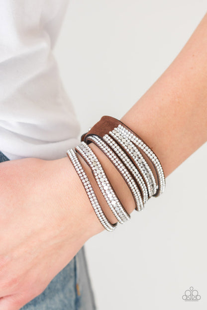 Rock Star Attitude Brown Wrap Bracelet - Paparazzi Accessories  Encrusted in rows of glassy white rhinestones and flat silver studs, three strands of brown suede wrap around the wrist for a sassy look. The elongated band allows for a trendy double wrap around the wrist. Features an adjustable snap closure.  Sold as one individual bracelet.