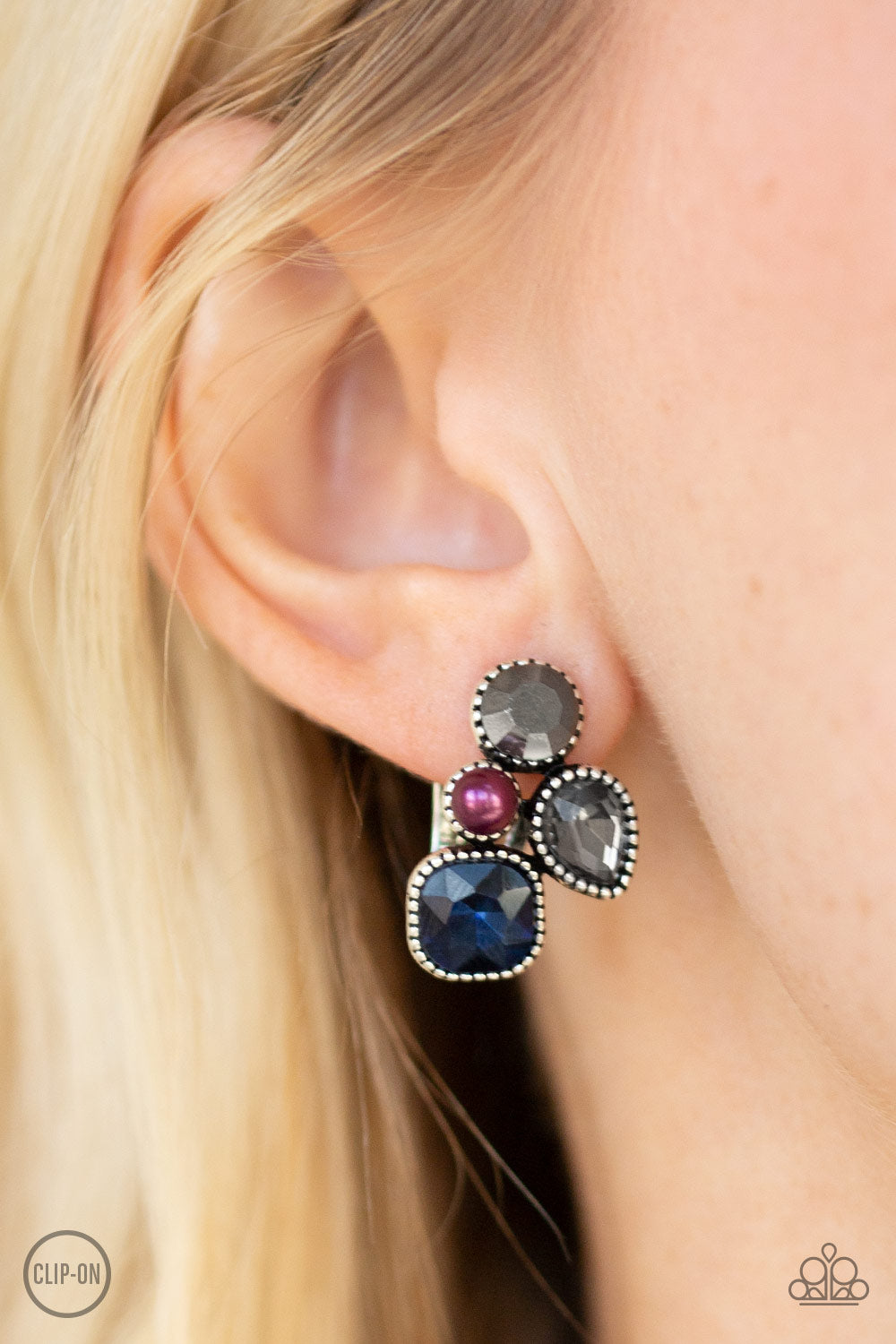 Super Superstar Multi Clip-On Earring - Paparazzi Accessories  Infused with a dainty purple pearl, mismatched blue, smoky, and hematite rhinestones coalesce into a glittery frame. Earring attaches to a standard clip-on fitting.   All Paparazzi Accessories are lead free and nickel free!  Sold as one pair of clip-on earrings.