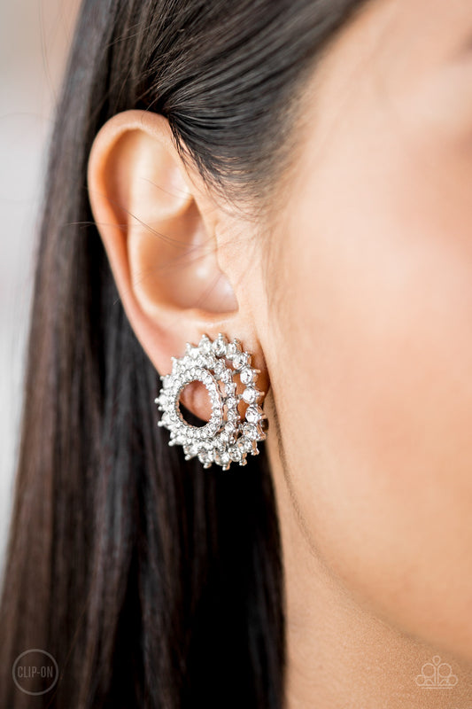 Buckingham Beauty White Clip-On Earring - Paparazzi Accessories  Gradually increasing in size, glassy white rhinestones are encrusted along three stacking silver frames for a regal look. Earring attaches to a standard clip-on fitting.  All Paparazzi Accessories are lead free and nickel free!  Sold as one pair of clip-on earrings.