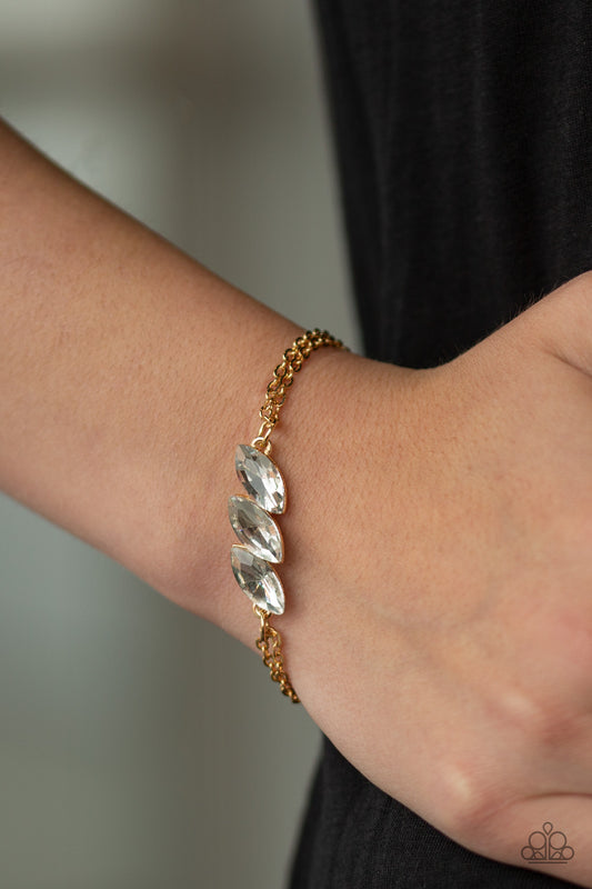 Pretty Priceless Gold Bracelet - Paparazzi Accessories.  Featuring regal marquise-cuts, a trio of glittery white rhinestones join across the center of the wrist for a timeless look. Features an adjustable clasp closure.  All Paparazzi Accessories are lead free and nickel free!   Sold as one individual bracelet.
