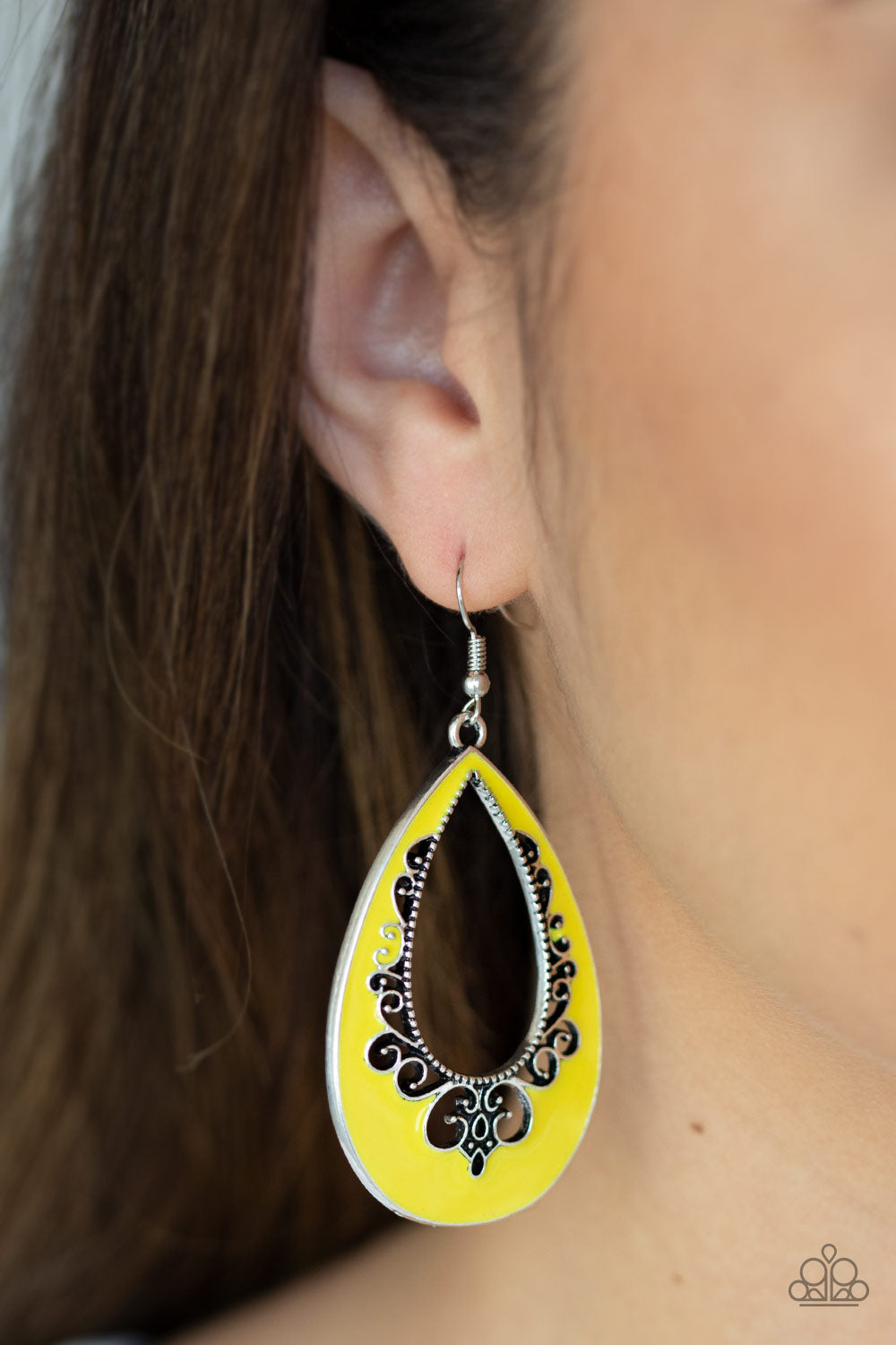 Compliments To The CHIC - Yellow Item #JJG-E302 Painted in a shiny yellow finish, an airy silver teardrop swings from the ear in a whimsical fashion. The colorful frame features cutout filigree patterns for a seasonal flair. Earring attaches to a standard fishhook fitting. All Paparazzi Accessories are lead free and nickel free!  Sold as one pair of earrings.