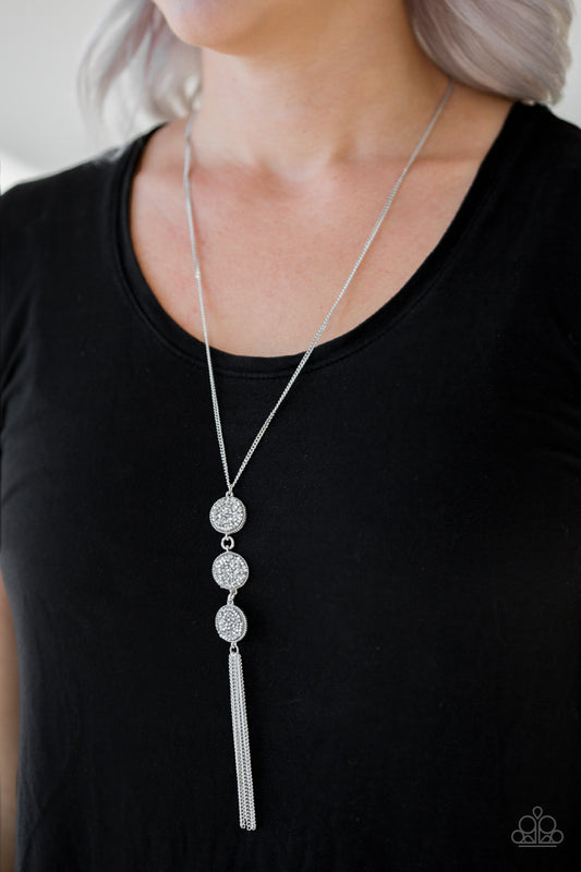 Triple Shimmer White Necklace - Paparazzi Accessories  Sprinkled in glassy white and smoky hematite prism style rhinestones, three sparkling silver frames trickle down the chest. A shimmery silver tassel swings from the bottom of the triple stacked pendant for a glamorous finish. Features an adjustable clasp closure.   Sold as one individual necklace. Includes one pair of matching earrings.