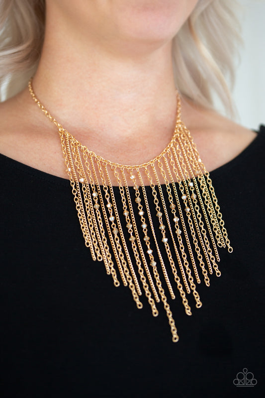 First Class Fringe Gold Necklace - Paparazzi Accessories  Varying in length, mismatched gold chains stream from the bottom of a classic gold chain. Faceted golden crystal-like beads sporadically dot the free-falling chains, creating a statement-making fringe below the collar. Features an adjustable clasp closure.  All Paparazzi Accessories are lead free and nickel free!  Sold as one individual necklace. Includes one pair of matching earrings.