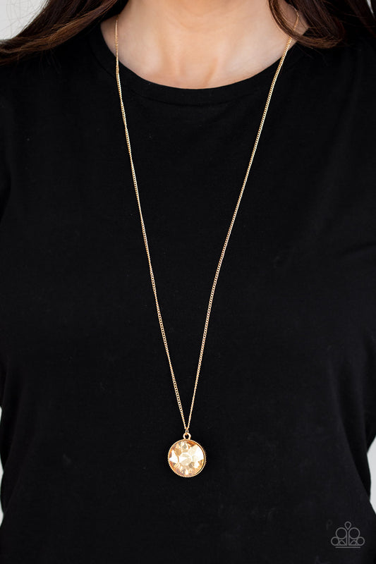 Dauntless Diva Gold Necklace - Paparazzi Accessories  An oversized golden gem swings from the bottom of a lengthened gold chain for a dramatic look. Features an adjustable clasp closure.  All Paparazzi Accessories are lead free and nickel free!  Sold as one individual necklace. Includes one pair of matching earrings.