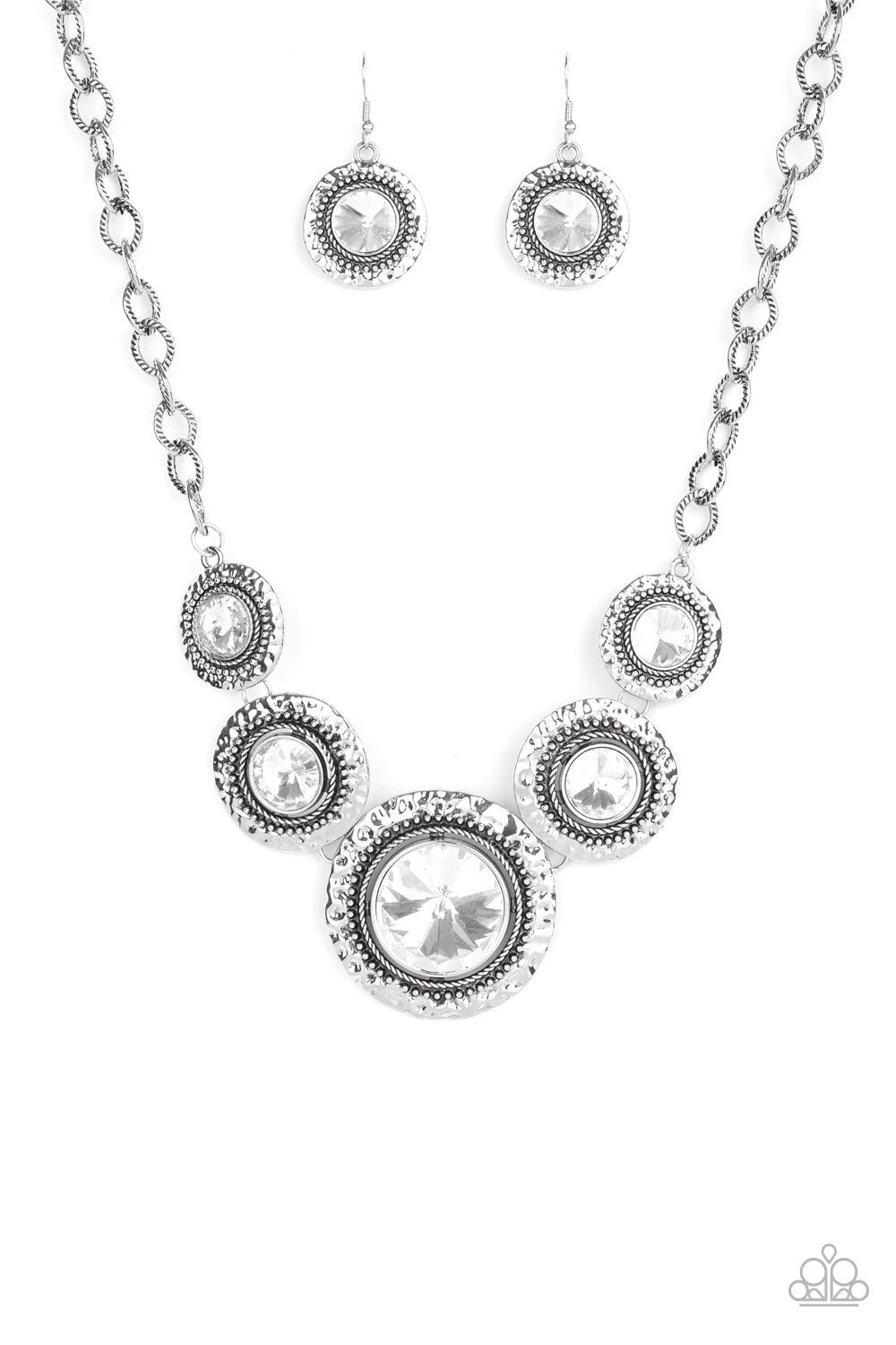 Global Glamour White Necklace - Paparazzi Accessories.  Gradually increasing in size, dramatically oversized white gems are pressed into the centers of hammered and silver studded frames. The blinding frames link below the collar for a glamorous, statement-making finish. Features an adjustable clasp closure.  ﻿All Paparazzi Accessories are lead free and nickel free!  Sold as one individual necklace. Includes one pair of matching earrings.