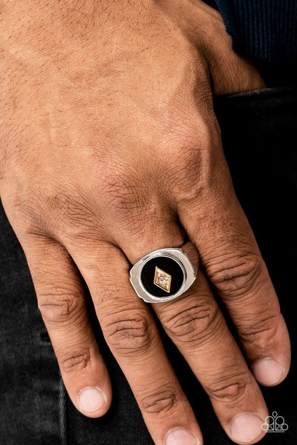 Alumni Black Urban Ring - Paparazzi Accessories   A solitaire white rhinestone is pressed into the center of a gold diamond-shaped frame that sits atop a painted black backdrop. Features a stretchy band for a flexible fit.  Sold as one individual ring.