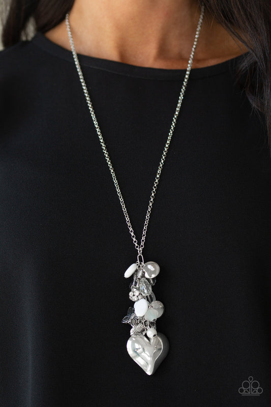 Beach Buzz White Necklace - Paparazzi Accessories. Infused with an array of white beads, a collection of antiqued silver shell and butterfly charms trickle along the bottom of a shimmery silver chain. Complemented with glittery white rhinestone encrusted beads, an oversized silver heart pendant swings from the bottom of the clustered tassel for a whimsical finish. Features an adjustable clasp closure.  All Paparazzi Accessories are lead free and nickel free! Includes one pair of matching earrings.
