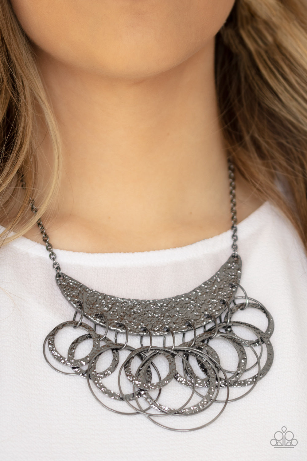 Metro Eclipse Black Necklace - Paparazzi Accessories  Hammered and embossed in a foil-like finish, a gunmetal moon-like frame bows below the collar. Dainty gunmetal hoops and matching hammered rings cascade from the bottom, creating an edgy fringe. Features an adjustable clasp closure.  Sold as one individual necklace. Includes one pair of matching earrings.
