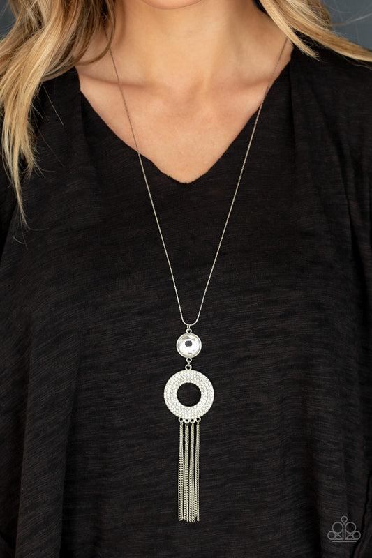 Sassy As They Come White Necklace - Paparazzi Accessories Item #N659 An oversized white gem attaches to a thick silver hoop encrusted in row after row of dazzling white rhinestones. Shimmery silver chains stream from the bottom of the stacked pendant at the bottom of a lengthened flat silver chain, creating a sassy tassel. Features an adjustable clasp closure. All Paparazzi Accessories are lead free and nickel free!  Sold as one individual necklace. Includes one pair of matching earrings.
