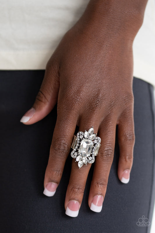 Things That Go Boom! - White A blinding collection of round and teardrop white rhinestones coalesce around an oversized emerald-style gem, creating a dramatic statement piece atop the finger. Features a stretchy band for a flexible fit.  Sold as one individual ring.