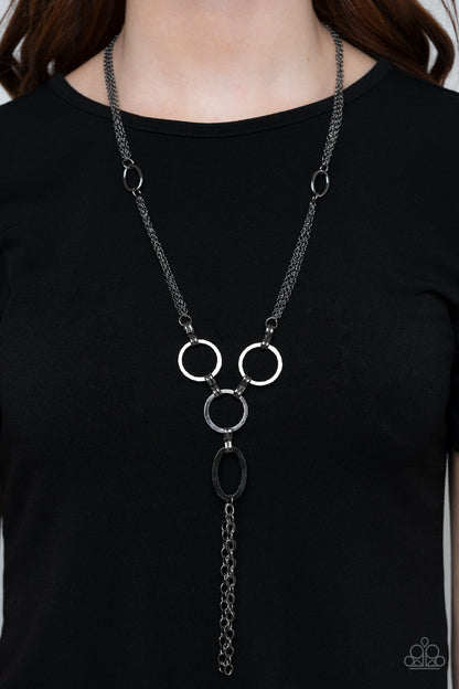 Metro Mechanics Black Necklace - Paparazzi Accessories. Hammered gunmetal rings and ovals link into an industrial style pendant at the bottom of shimmery sections of gunmetal chains. Classic gunmetal chains stream from the bottom of the display, adding edgy movement. Features an adjustable clasp closure.  All Paparazzi Accessories are lead free and nickel free!  Sold as one individual necklace. Includes one pair of matching earrings.