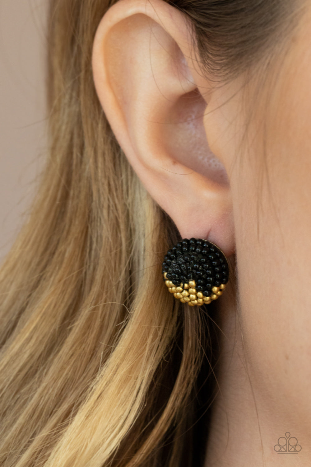 As Happy As Can BEAD - Black Item #P5PO-BKXX-150XX A dainty collection of black and brassy seed beads embellished the front of a circular frame, creating a colorful half and half pattern. Earring attaches to a standard post fitting.  Sold as one pair of post earrings.