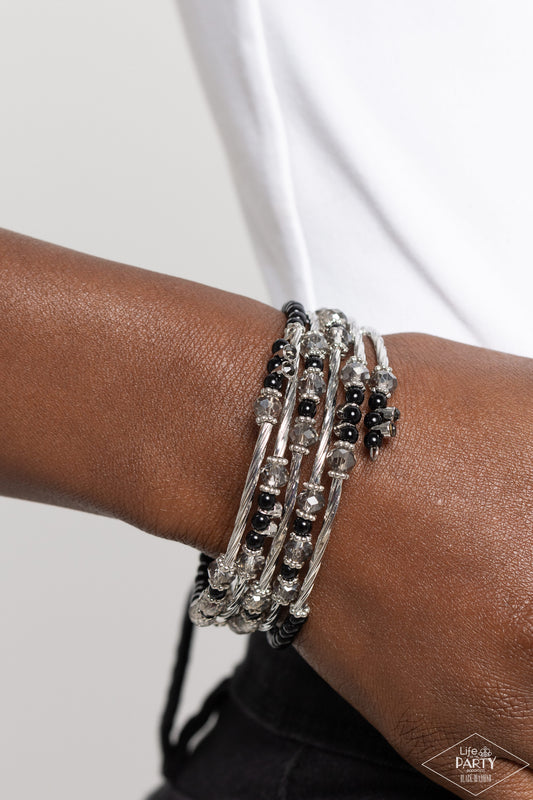 Head-Turning Twinkle Black Coil Bracelet - Paparazzi Accessories  A glamorous collection of black beads, glassy white rhinestones, dainty silver beads, smoky crystal-like accents and textured silver rods are threaded along a coiled wire, creating a glittery infinity wrap style bracelet around the wrist.  Sold as one individual bracelet.  SKU: P9RE-BKXX-292XX