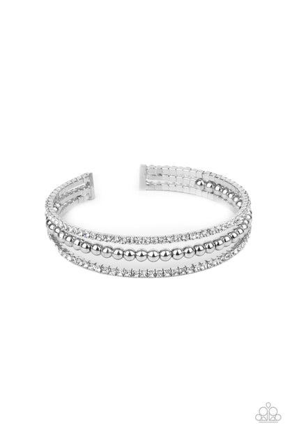High-End Eye Candy White Cuff Bracelet - Paparazzi Accessories. Two strands of dazzling white rhinestones flank a row of shiny silver beads, coalescing into a sparkly layered cuff around the wrist.  All Paparazzi Accessories are lead free and nickel free!  Sold as one individual bracelet.