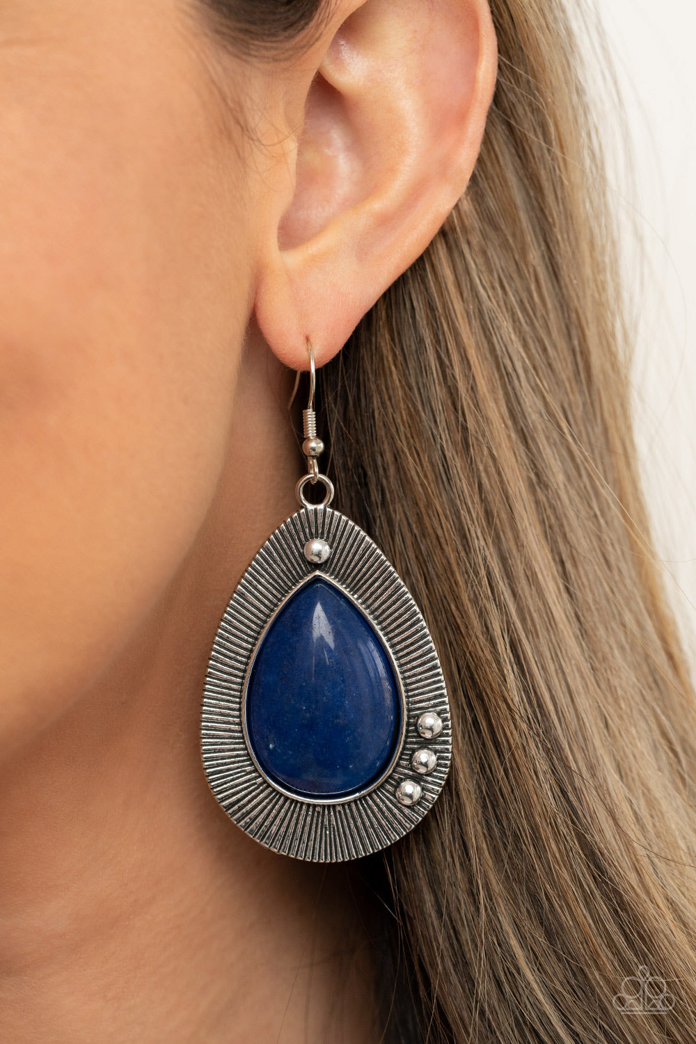 Western Fantasy Blue Earring - Paparazzi Accessories  Chiseled into a tranquil teardrop, a shimmery French Blue stone bead is pressed into the center of a rustically studded silver frame radiating with antiqued detail for a southwestern flair. Earring attaches to a standard fishhook fitting.  All Paparazzi Accessories are lead free and nickel free!  Sold as one pair of earrings.