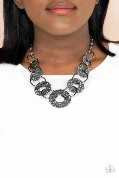 Industrial Envy Black Necklace - Paparazzi Accessories  Gradually increasing in size near the center, a collection of glistening gunmetal rings and abstract hammered discs interlock below the collar for an intense industrial look. Features an adjustable clasp closure.  All Paparazzi Accessories are lead free and nickel free!  Sold as one individual necklace. Includes one pair of matching earrings.