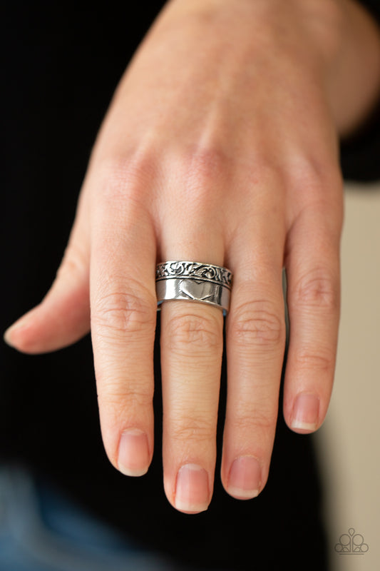 Garden Romance Silver Ring - Paparazzi Accessories  Bordered in a leafy embossed trim, a thick silver band is embossed in a heart for a vintage inspired look. Features a stretchy band for a flexible fit.  All Paparazzi Accessories are lead free and nickel free!  Sold as one individual ring.